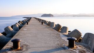 冬の朝、瀬戸内海に面した広島の堤防と穏やかな海。遠くに島影が見える
