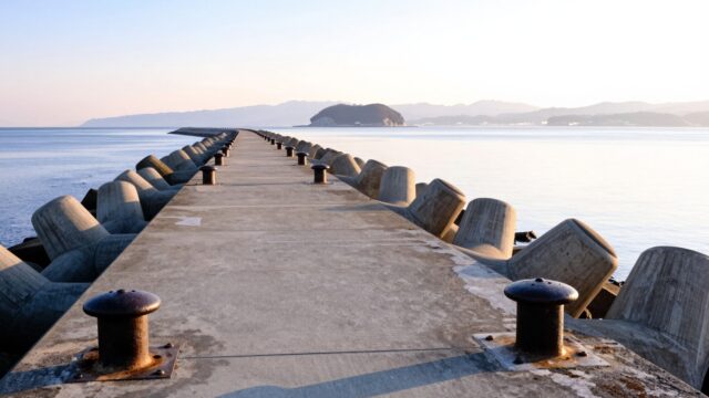 冬の朝、瀬戸内海に面した広島の堤防と穏やかな海。遠くに島影が見える