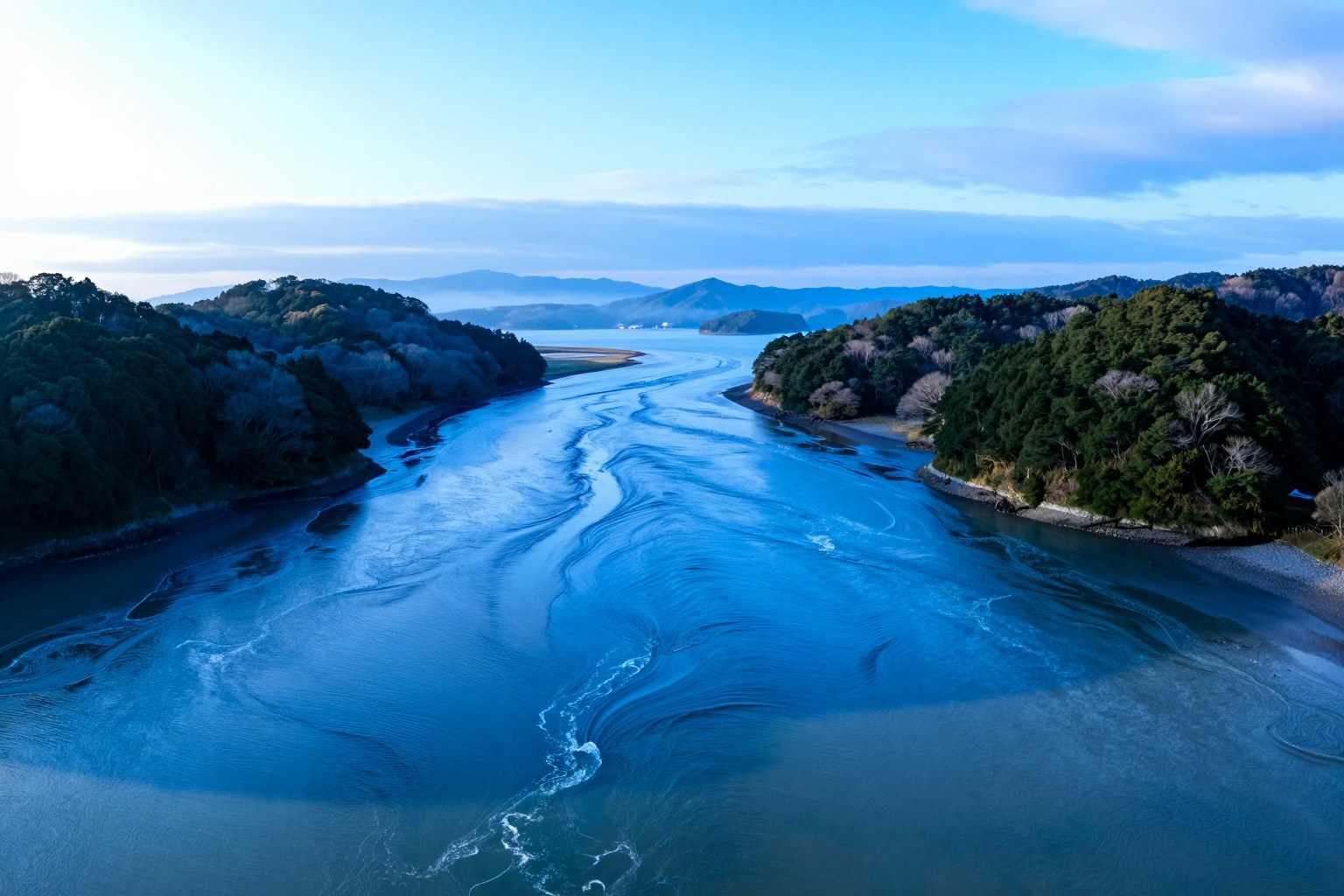 朝の瀬戸内海。島と島にはさまれた水道で、潮の流れが水面に筋をつくっている様子を高い位置から広く見渡した風景